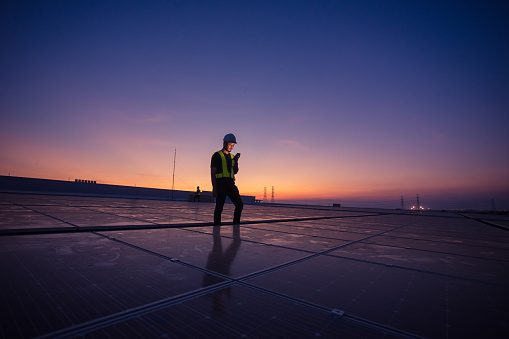 Engineer service check installation solar cell on the roof of factory on the morning.