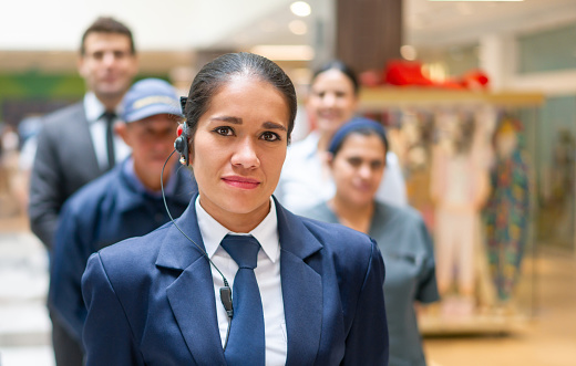 Portrait of a Latin American Security guard with a group of workers at a shopping mall - staff concepts