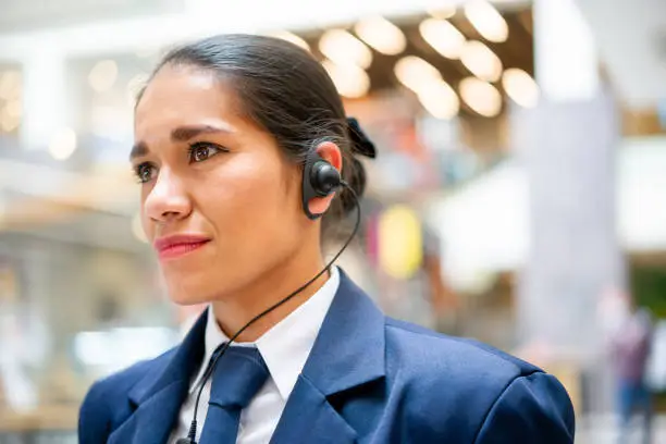 Portrait of a Latin American female security guard working at a shopping mall and wearing a headset