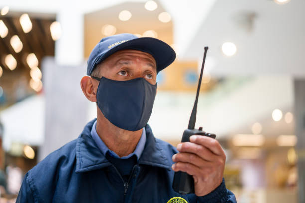 guardia giurata che indossa una maschera facciale mentre lavora in un centro commerciale - security security guard event protection foto e immagini stock