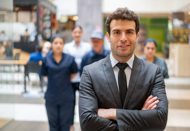 Portrait of a Latin American manager with a group of his workers at a shopping mall and looking at the camera smiling - reopening of businesses