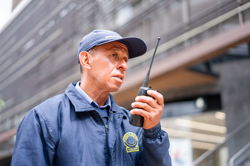 Portrait of a Latin American security guard outdoors working at a shopping mall and talking on the CB radio