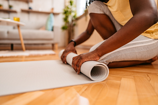 Young African-American woman rolling her exercise mat after her home workout.