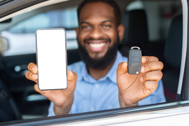 istock Car Renting App. Black Man Showing Key And Smartphone With Blank Screen 1331288697