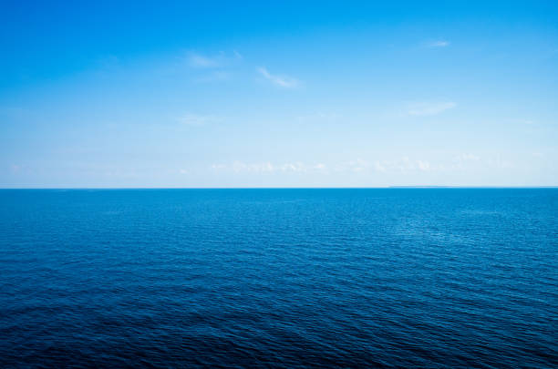 Tranquil minimalist landscape with a smooth blue sea surface with calm waters with a horizon and clear skies. Simple beautiful natural calm background. Copy space.
