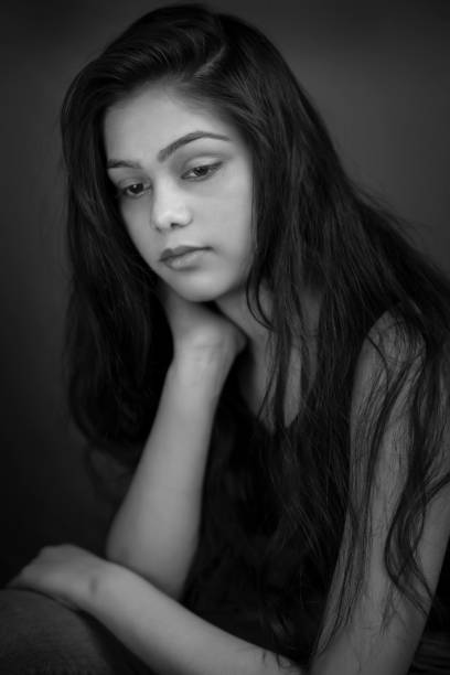 retrato preto e branco de uma jovem triste contemplando com uma expressão em branco. - teenager dark pensive emotional stress - fotografias e filmes do acervo