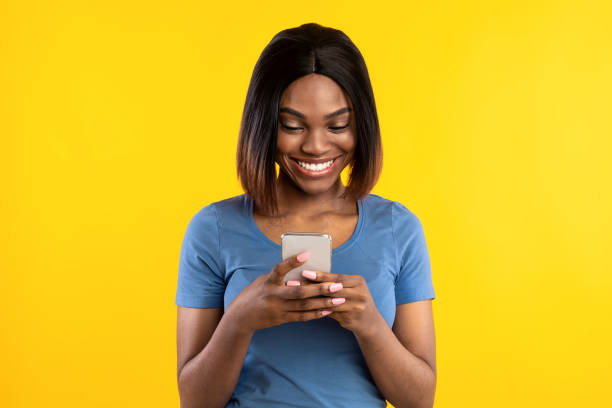 istock African American Lady Using Cellphone Texting Over Yellow Studio Background 1331290746