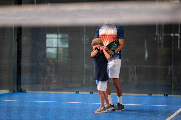 monitor de enseñanza de la clase de pádel para el hombre, su estudiante - entrenador enseña a los niños a jugar al pádel en la pista de tenis cubierta - tennis indoors court ball fotografías e imágenes de stock