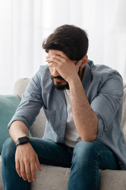 istock Male depression concept. Desperate arab man touching his forehead, having problems, sitting on sofa at home, crop 1331293544