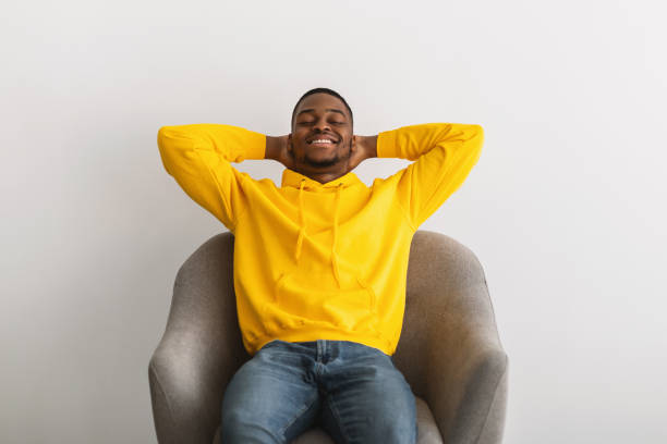 istock Black Guy Sitting With Hands Behind Head In Armchair Indoor 1331293755
