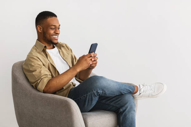 istock Happy African American Man Using Smartphone Sitting On Gray Background 1331293884
