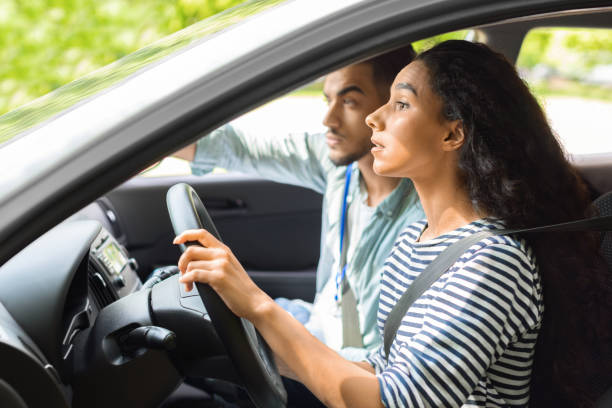 istock Nervous young lady driving school student driving car with instructor 1331293970