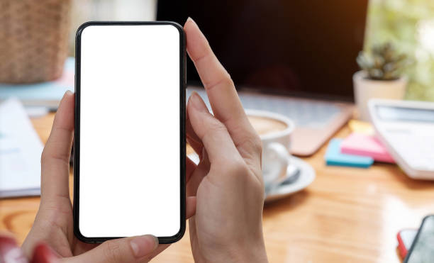 istock Mockup image blank white screen cell phone.women hand holding texting using mobile on desk at home office. 1331296428