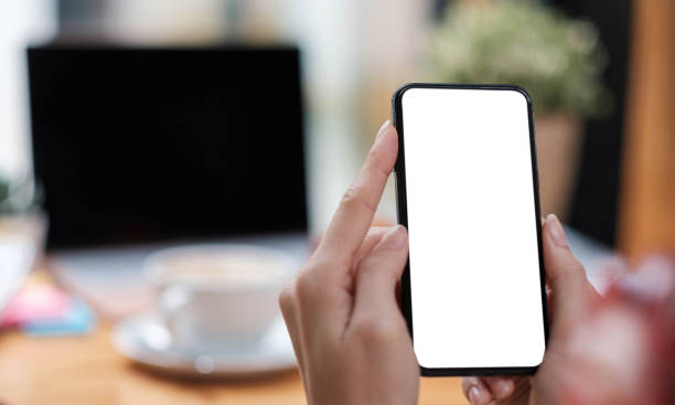 istock Mockup image blank white screen cell phone.women hand holding texting using mobile on desk at home office. 1331296454