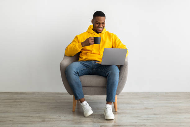 istock Cheerful Black Man Working On Laptop Drinking Coffee Sitting Indoors 1331296480