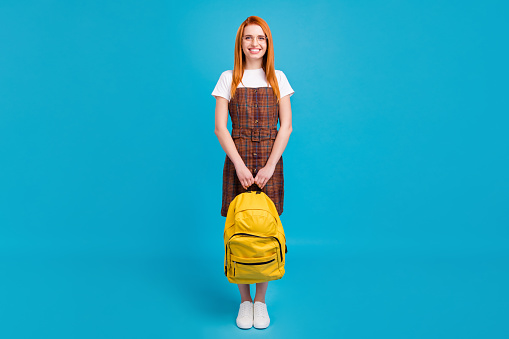 Photo of charming adorable orange hair lady wear plaid overall spectacles holding rucksack isolated blue color background