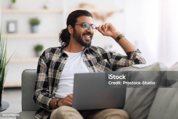 Dreamy Arab Guy Freelancer Working From Home Using Laptop Stock Photo - Download Image Now