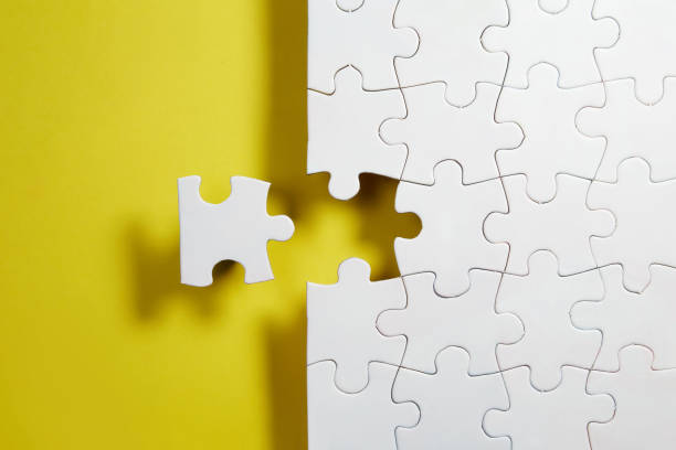 istock Unfinished white jigsaw puzzle pieces on yellow background 1331298420