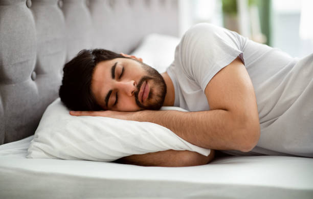 istock Comfortable sleep. Millennial arab man sleeping peacefully and see sweet dreams, lying in comfy bed and hugging pillow 1331298484