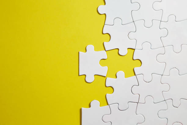 istock Unfinished white jigsaw puzzle pieces on yellow background 1331299056