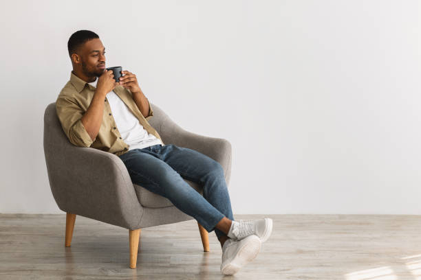 istock Black Man Enjoying Coffee Sitting In Chair On Gray Background 1331299305