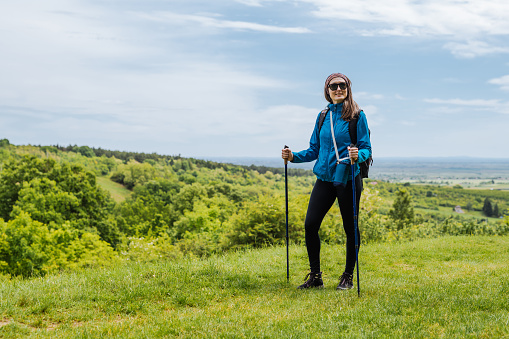 Mid adult woman hiking in springtime with small backpack and poles