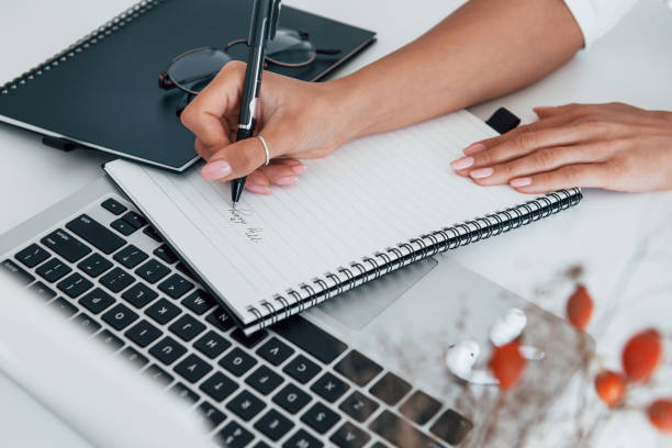 istock Using laptop and notepad. Young female freelancer working indoors in the office at daytime 1331300206