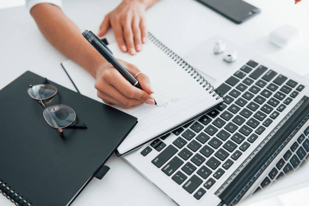 istock Using laptop and notepad. Young female freelancer working indoors in the office at daytime 1331300280