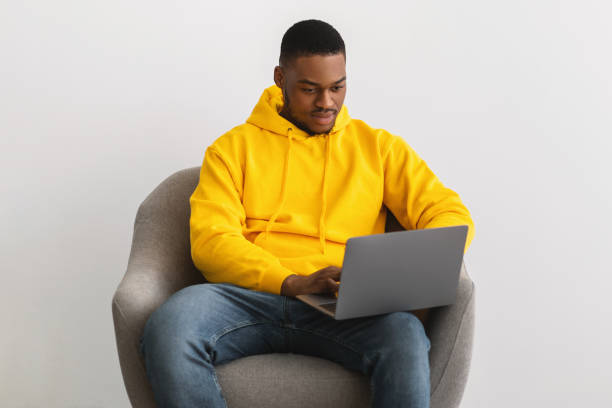 istock African Man Using Laptop Working Online In Armchair, Gray Background 1331301495