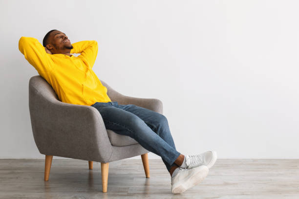 istock Black Guy Relaxing Sitting In Comfortable Chair Over Gray Wall 1331301595