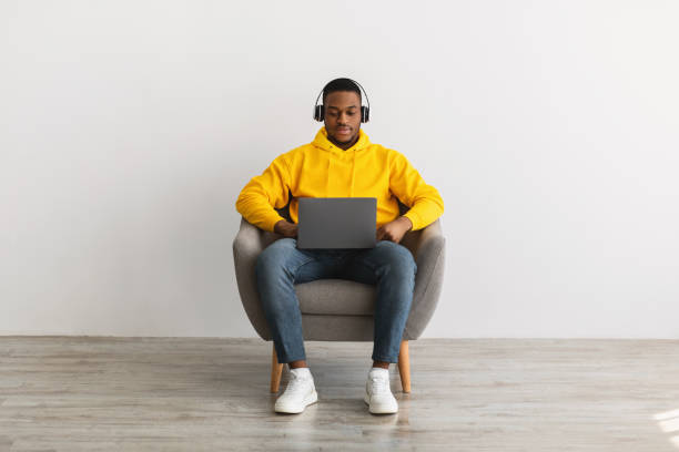 istock Serious African Guy Using Laptop Wearing Headphones Over Gray Wall 1331302359