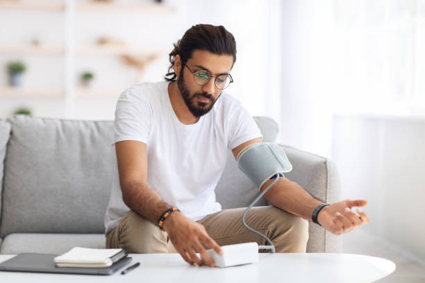 man sitting checking blood pressure at home - garment emotional stress equipment household equipment imagens e fotografias de stock