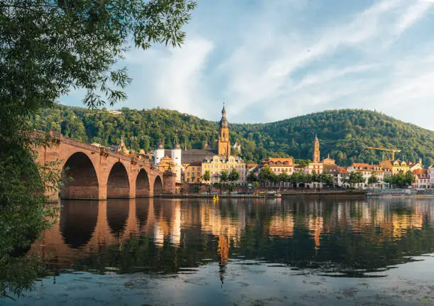 The old town (Atlstadt) and old bridge of Heidelberg, Germany reflected in the calm water of the Neckar river on a sunny summer afternoon