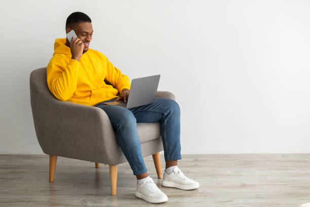 istock African Guy Talking On Cellphone Using Laptop Over Gray Wall 1331303066