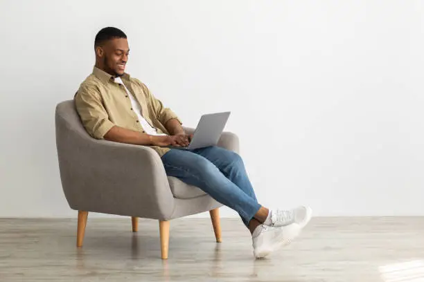 Photo of Side-View Of Black Freelancer Man Using Laptop Working Online Indoors
