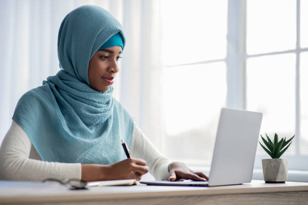 istock Online Learning Concept. Black Muslim Lady In Hijab Using Laptop At Home 1331303879