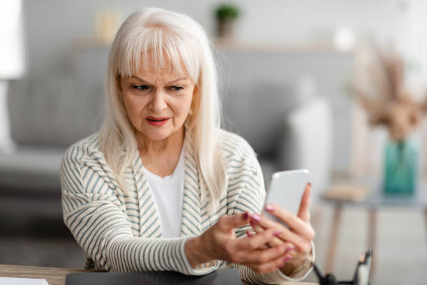 confused senior woman using her mobile phone - kvinna telefonbedragare bildbanksfoton och bilder