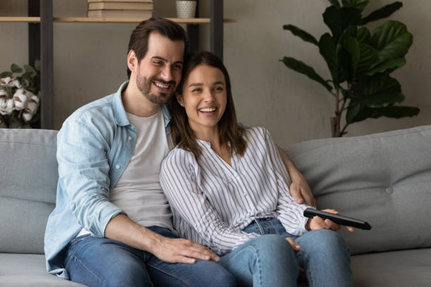 istock Laughing couple watching internet television relaxing on sofa at home 1331304102