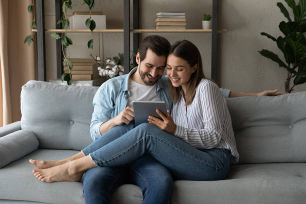 istock Couple in love sit on sofa with modern tablet device 1331304104