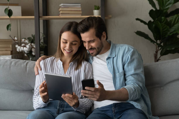 istock Couple sit on sofa with modern diverse gadgets 1331304107