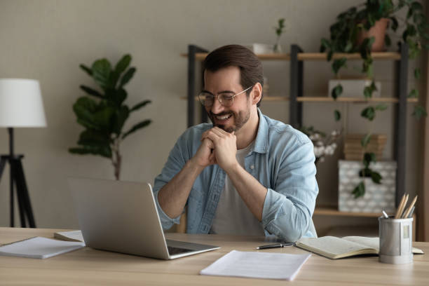 istock Man sit at desk smiling looking at laptop screen 1331304119