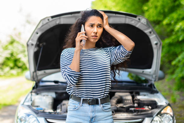 Nervous woman with open car hood calling auto service Nervous young woman standing by open car hood and calling to auto service, got broken at highway on a way to countryside. Female drive having phone conversation with friends, asking for help with auto broken spring stock pictures, royalty-free photos & images