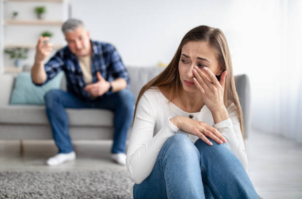 mature man abusing his depressed wife, shouting, humiliating and threatening her, middle aged woman crying at home - arguing senior adult conflict couple imagens e fotografias de stock