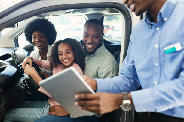 famiglia nera testa auto nuova, venditore mostra loro acquisto o contratto di locazione su tablet digitale presso concessionaria auto - car african descent shopping car dealership foto e immagini stock