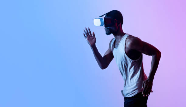 istock Virtual sports. Young black guy jogging while wearing VR headset in neon light, panorama with free space 1331306426