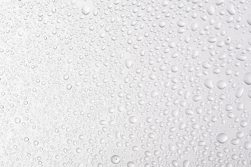 Pure water droplets condense on the glass on a white background giving a clean, fresh feeling. clear water droplets on glass.