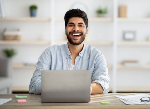 istock Portrait of successful arab freelancer sitting at workplace with laptop computer and smiling at camera, copy space 1331306714