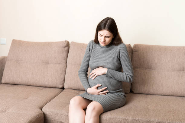 istock Pregnant Lady Having Massaging Lower belly Sitting On Sofa Indoor. Pregnancy Problems Concept. Maternity healthcare 1331308159