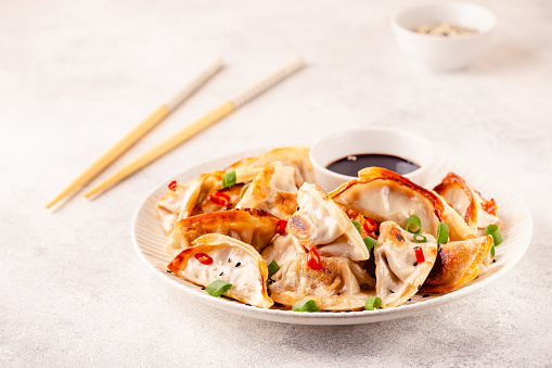 Fried dumplings served with green onions, sesame seeds and chili peppers.