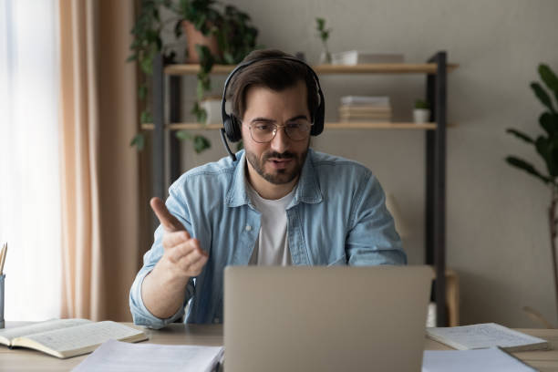 istock Man wear headset looks at laptop screen and talking 1331313433